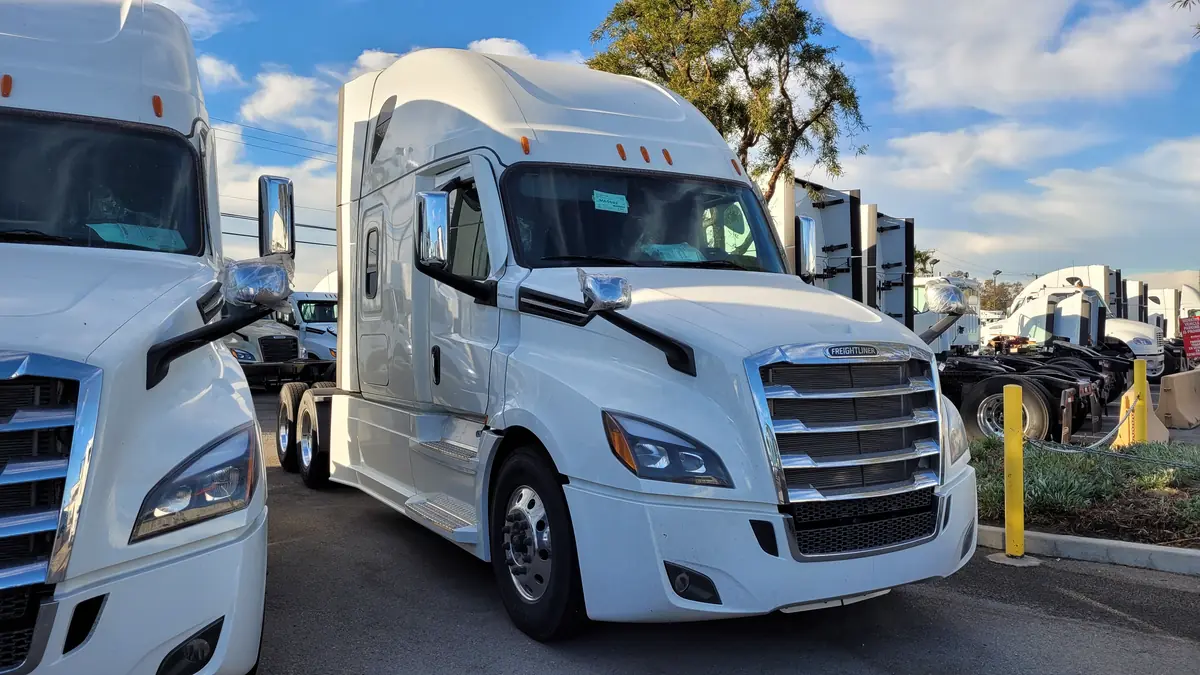 New white Freightliner Cascadia sleeper tractors parked on a truck dealership lot in Fontana, California