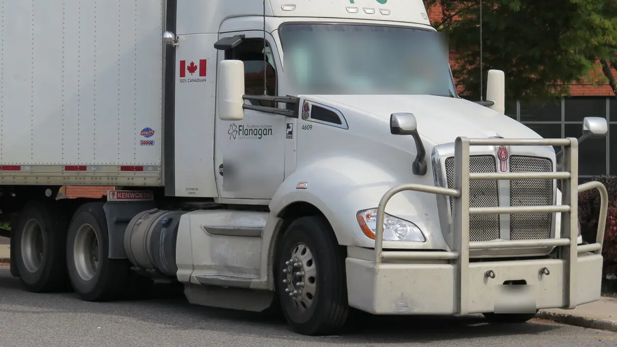 White 2022 Kenworth T680 day cab tractor with a dry van trailer parked on a street